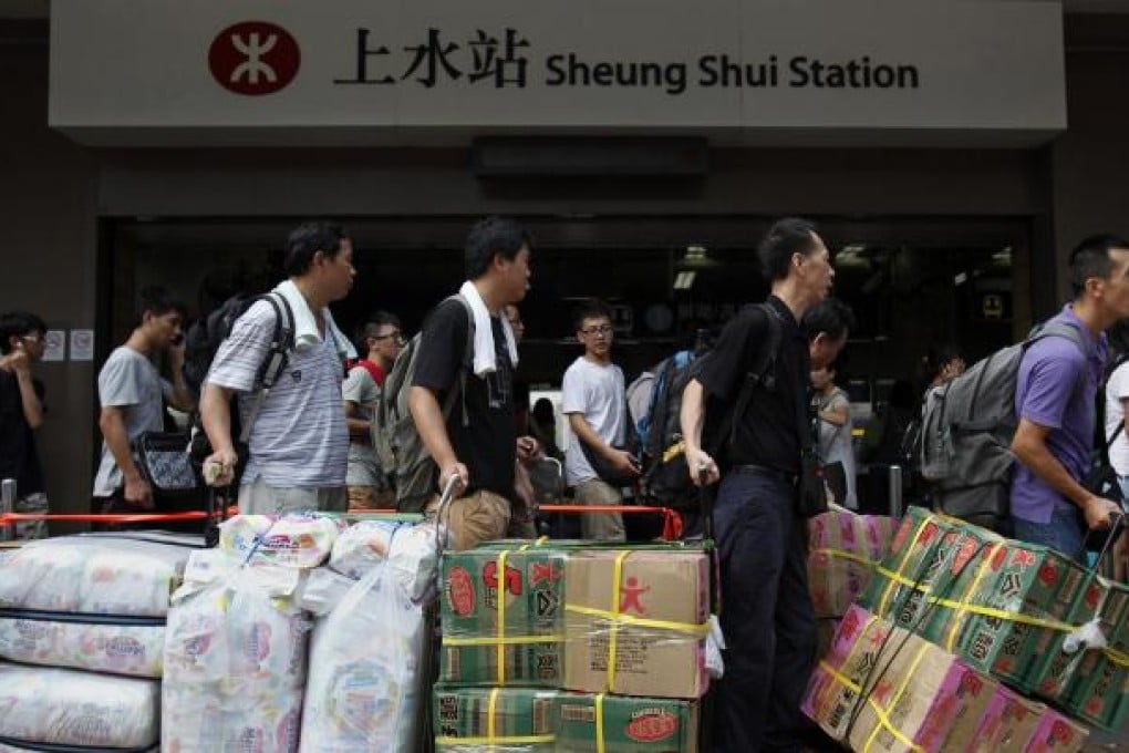 Mainland Chinese visitors line up at Hong Kong's Sheung Shui train station with boxes of instant noodles and packages of diapers to be parallel imported into Shenzhen for resale. Photo: Reuters