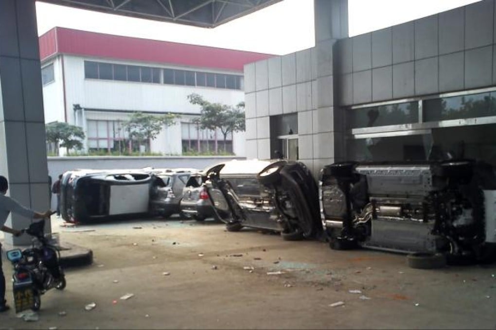 Cars parked inside a Nissan dealership are seen damaged and overturned during anti-Japan protests. Photo: Reuters