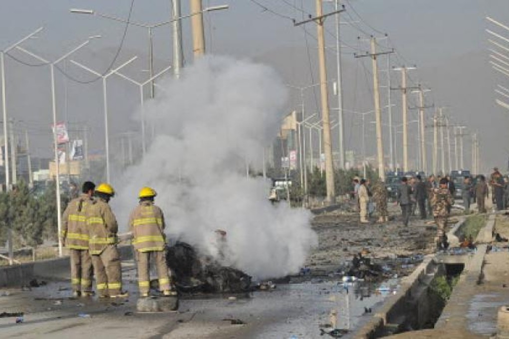 Afghanistan firefighters pour water on the remains of a vehicle that carried suicide attackers at the site of a bombing in Kabul on Tuesday. Photo: AFP
