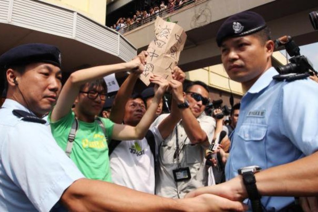 Protesters demonstrate against cross-border parallel traders - who they complained obstruct roads and distort the local economy - outside an exit to Sheung Shui station yesterday. Photo: Felix Wong
