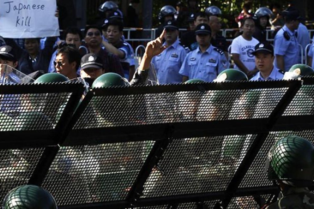 An anti-Japan protester argues with police guarding a barricade outside the Japanese embassy in Beijing on Tuesday. Photo: AP