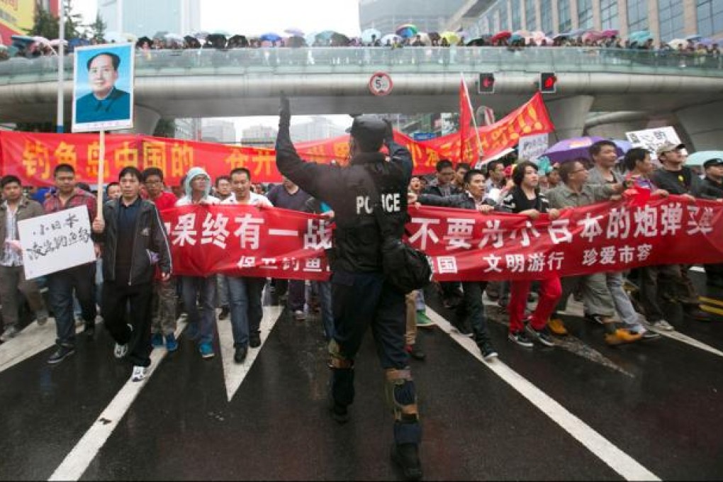 A Chinese riot policeman (centre) directs protesters as they march and display anti-Japanese banners during a protest over the Diaoyu islands issue. Photo: AFP