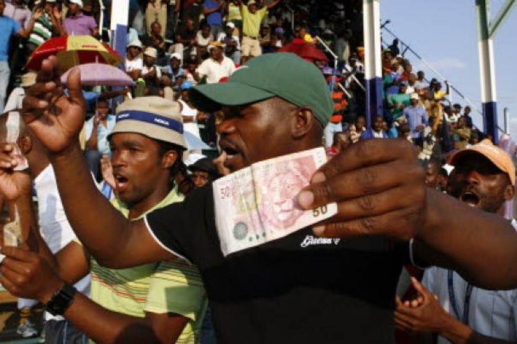 Miners sing and dance while holding South African bank notes in Lonmin Platinum Mine on Tuesday. Striking miners have accepted an offer of a  22 per cent pay increase to end more than five weeks of industrial action. Photo: AP