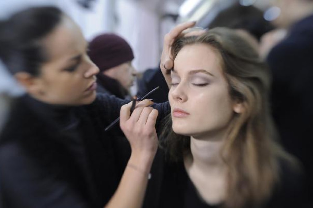 A make-up artist applies the barely there smoky-eye look backstage at Valentino's autumn-winter fashion show.