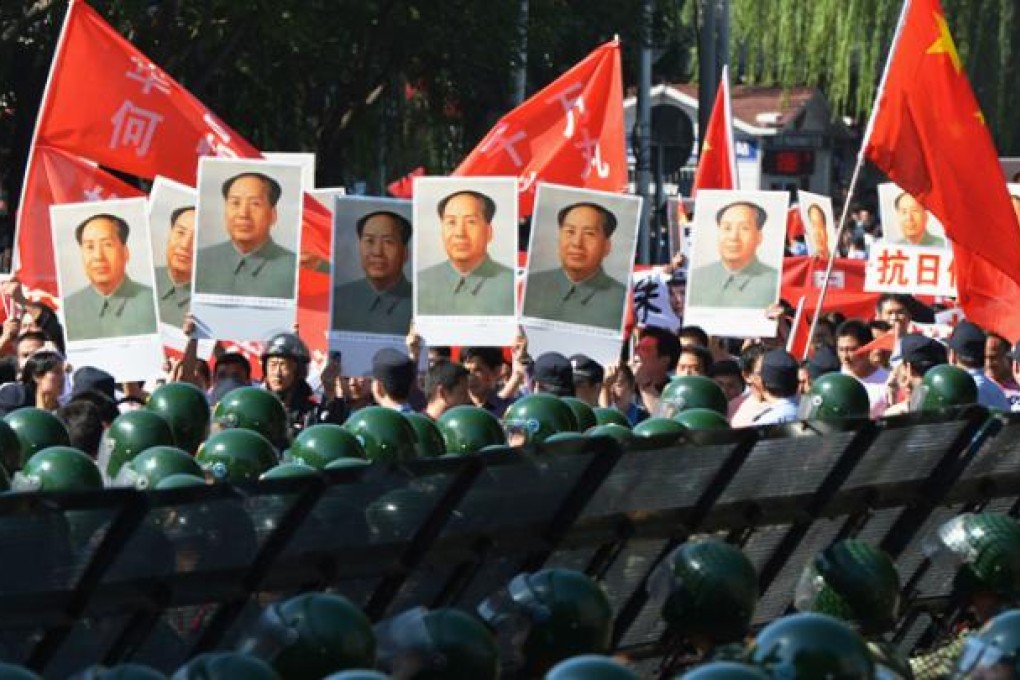 Demonstrators march holding images of former Chinese leader Mao Zedong as police stand guard outside the Japanese embassy in Beijing on Tuesday. Photo: AFP