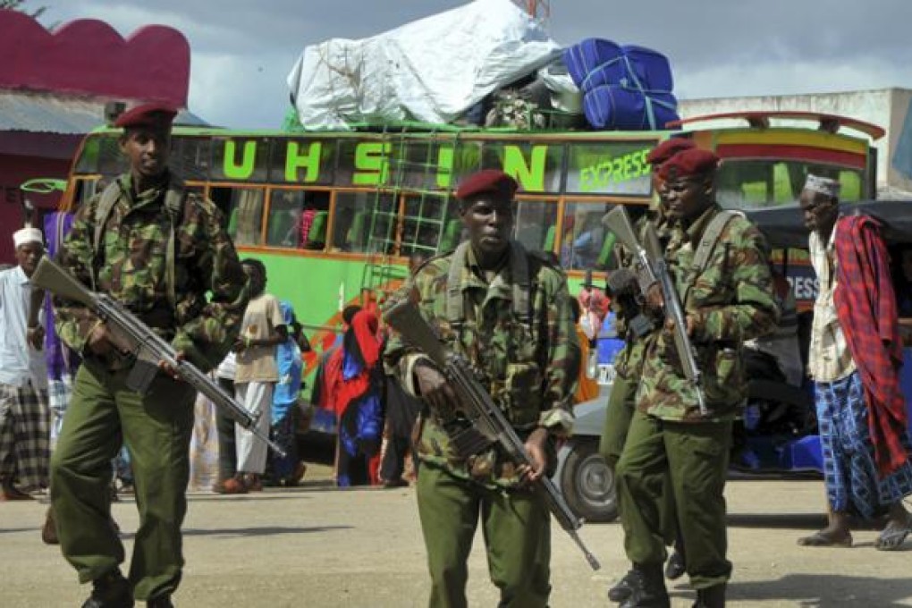 Kenyan police officers patrol in the town of Garsen, as residents pile their belongings onto a bus to leave, in the Tana River area on Saturday. Photo: AP