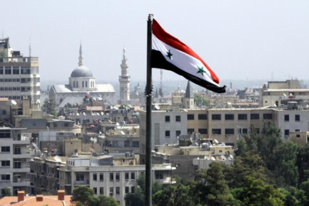 The Syrian flag flutters above Damascus on Thursday. Photo: AFP