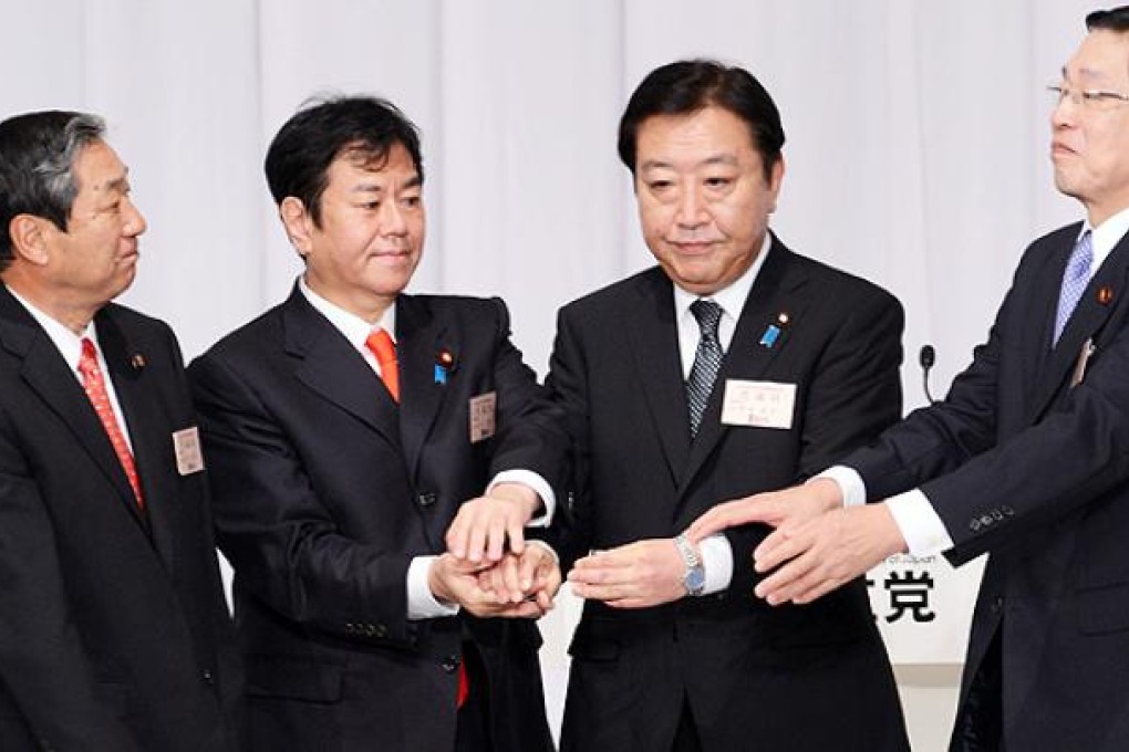Japanese Prime Minister and re-elected ruling Democratic Party of Japan (DPJ) leader Yoshihiko Noda (second right) holds hands with other DPJ presidential election candidates in Tokyo on Friday. Photo: AFP