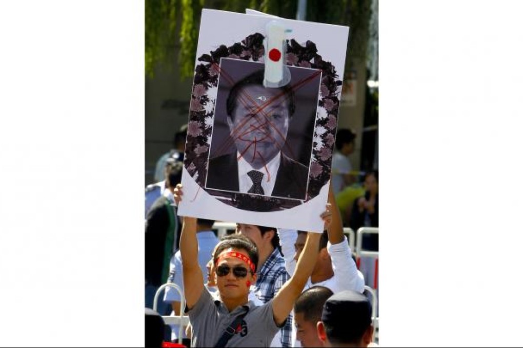 A protester at Japan's embassy in Beijing with a banner showing Prime Minister Noda. Photo: EPA