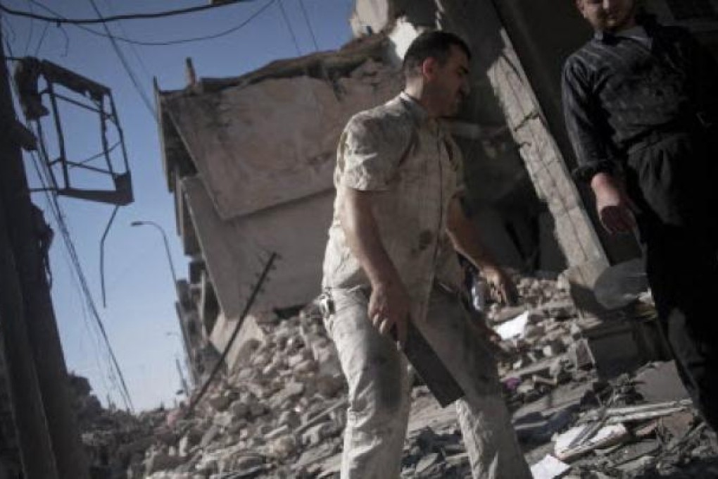 Syrian men salvage belongings from a destroyed buildings in the Bustan al-Qasr neighborhood of Aleppo. On Saturday, 11 Syrian soldiers were killed fighting in Aleppo. Photo: AP