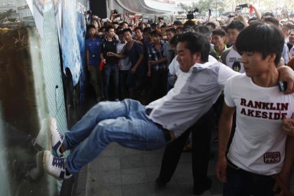 A demonstrator tries to smash the window at a department store of the Japanese Seibu chain in Shenzhen last week. Photo: Reuters
