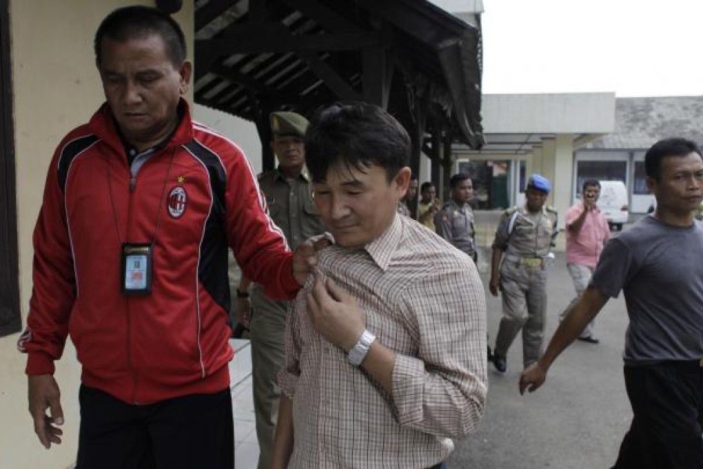 An official escorts an Afghan asylum seeker. Photo: Reuters