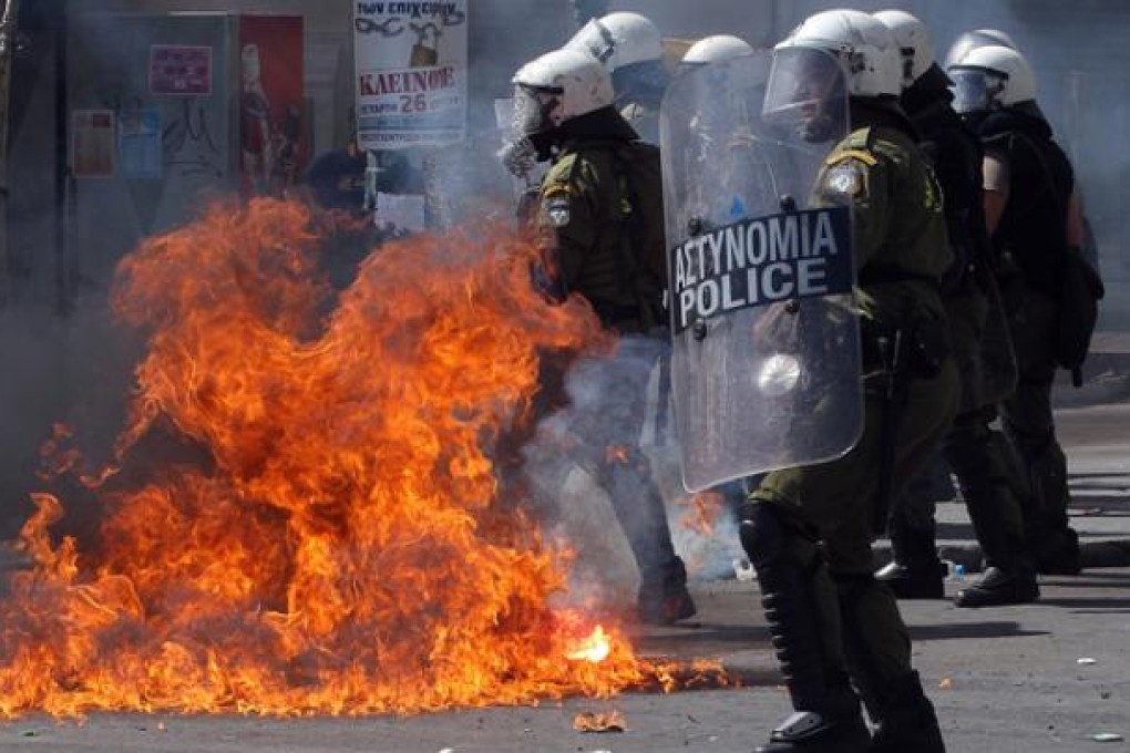 Riot police stand in front of flames caused by a thrown molotov cocktail during violent clashes demonstration in Athens on Wednesday. Photo: EPA