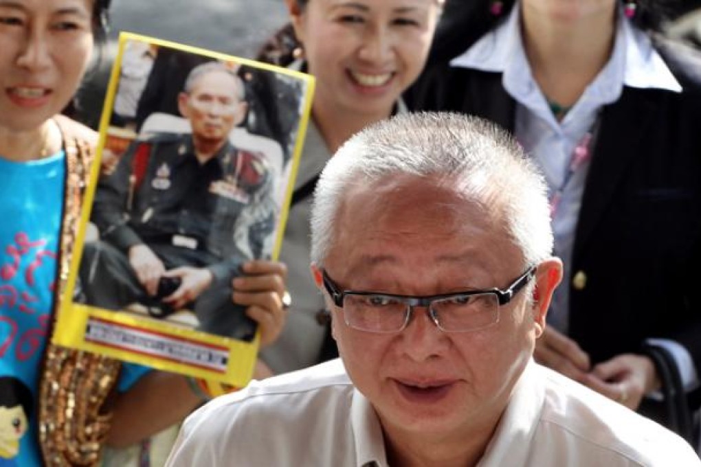 Sondhi Limthongkul passes supporters with one carrying the picture of King Bhumibol Adulyadej at the criminal court in Bangkok on Wednesday. Photo: AP