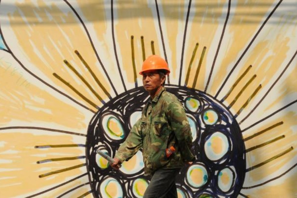 A construction worker walks past a billboard in Shanghai. Ratings agencies have trimmed expectations for the economy. Photo: AFP