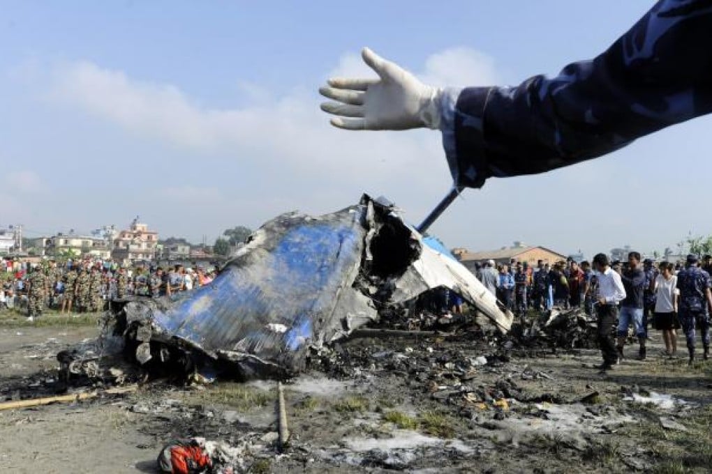 Nepalese rescue team members gather around at the remains of the Sita aircraft, which was heading towards Mount Everest. Everyone on board died. Photo: AFP