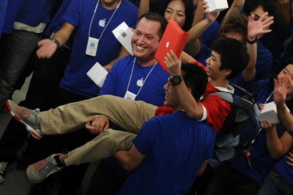 Apple store employees carry their first customer into the company's new store in Hong Kong on Saturday. Photo: AFP
