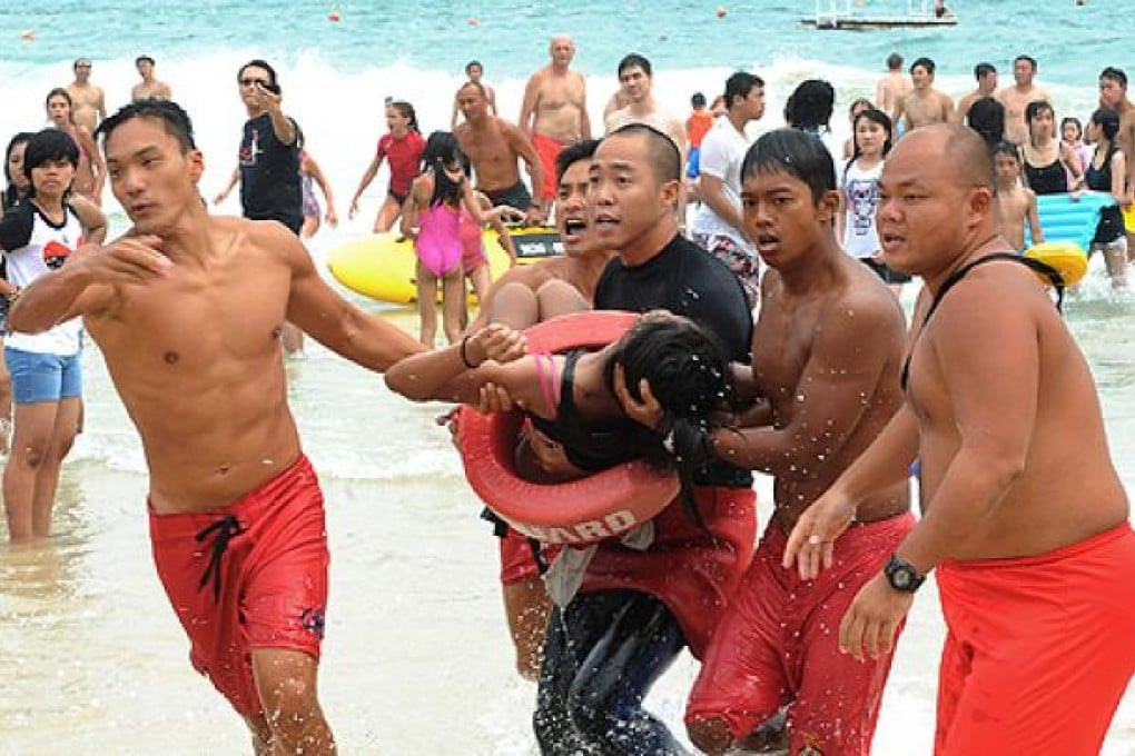 Lifeguards rescue a girl from the ocean after she and her friends were swept away in strong waves at Shek O beach. Photo: SCMP Pictures