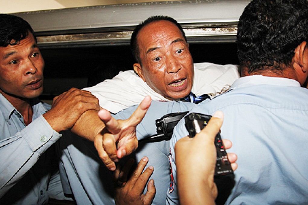 Beehive Radio station owner Mam Sonando is escorted by police officers at the court in Phnom Penh on Monday. Photo: EPA