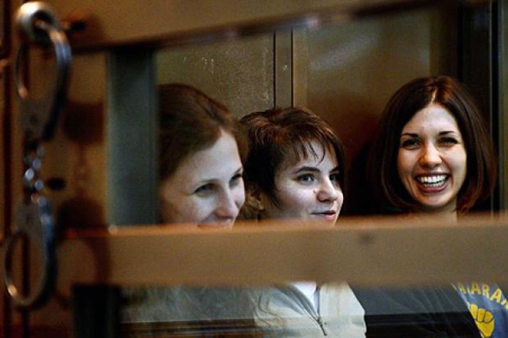 (From left) Yekaterina Samutsevich, Maria Alyokhina and Nadezhda Tolokonnikova sit in a glass-fronted cage during the hearing in a packed Moscow city court on Monday. Photo: AFP