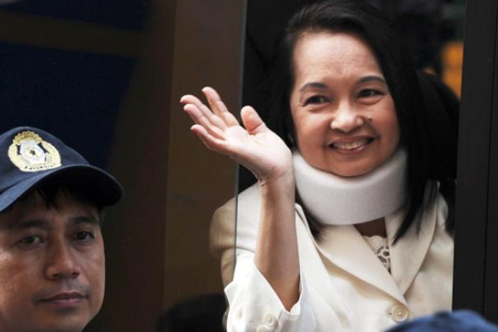 Former Philippine president Gloria Arroyo waves to photographers from a vehicle after appearing in court for her arraignment in February. Photo: AFP