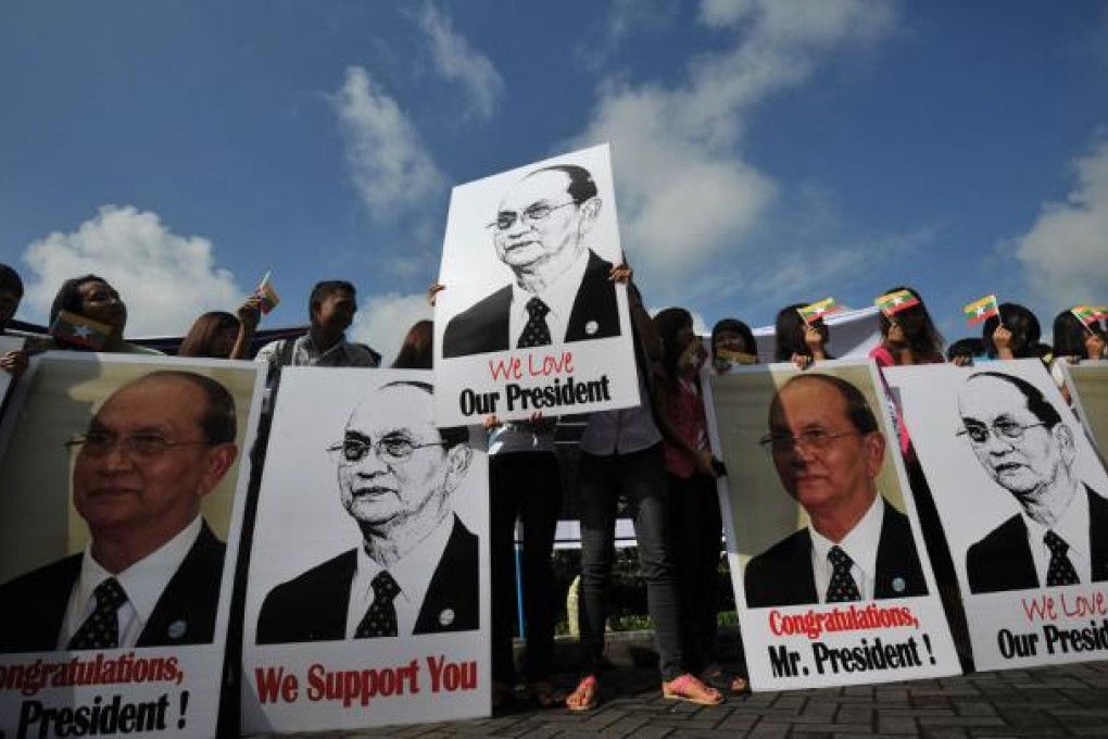 Supporters hold pictures of Myanmar president Thein Sein as they welcome him at Yangon International Airport. Photo: AFP