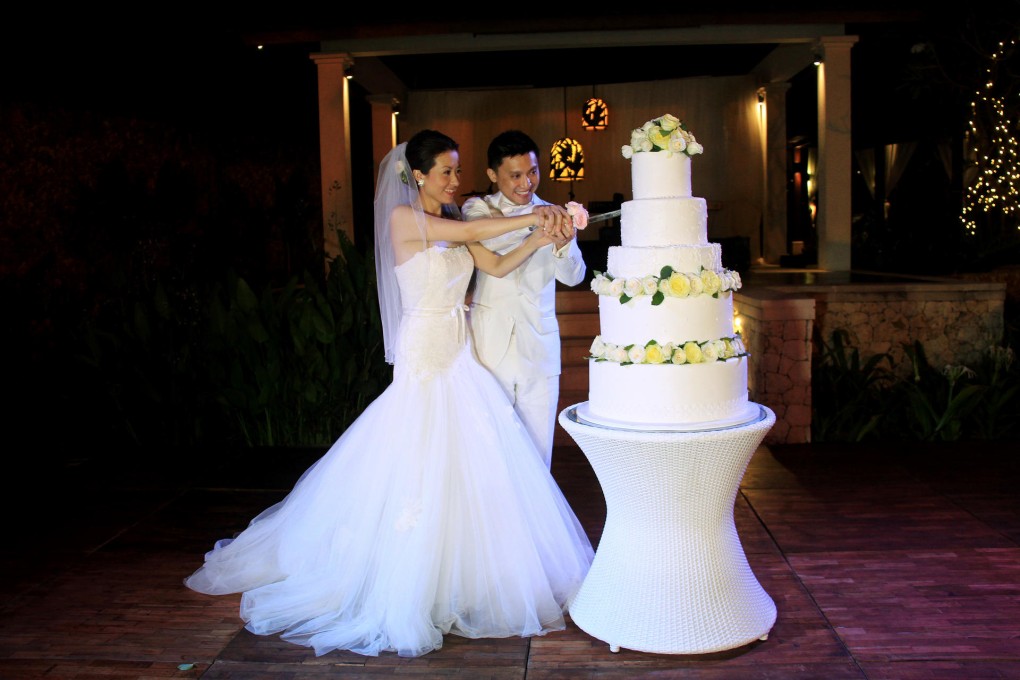 Peter Hwang and Virginia Wang get to grips with their five-tier cake at their wedding in Bali.