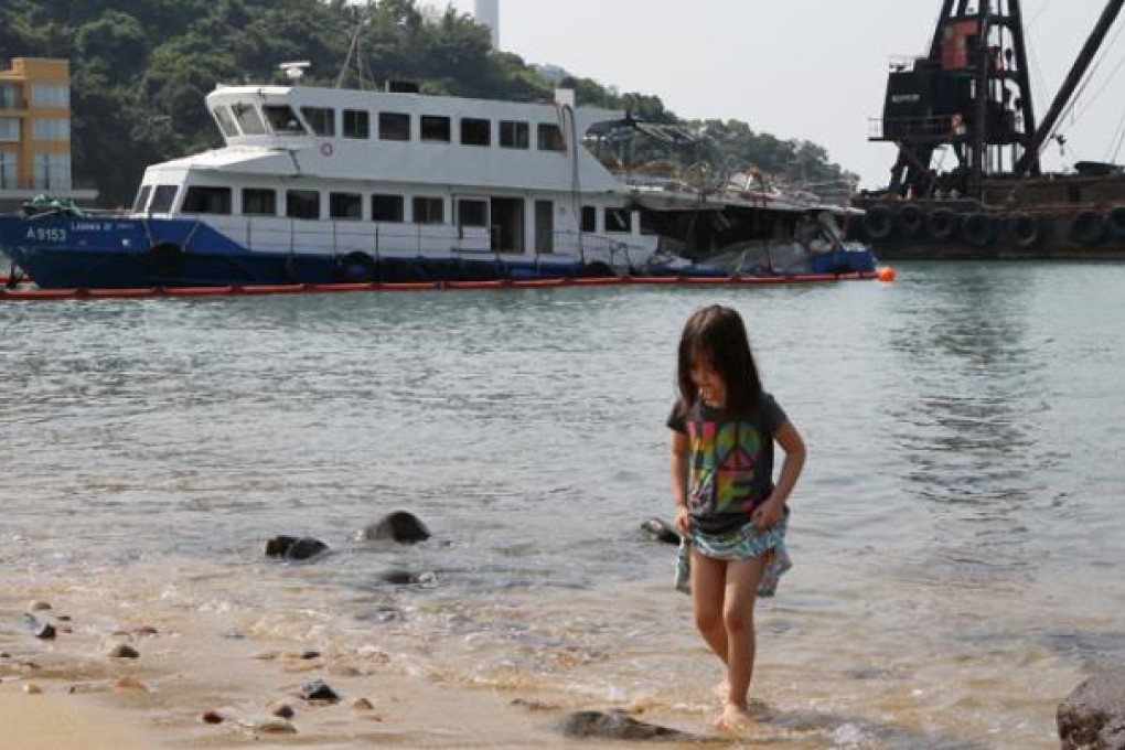 A child plays on a beach near the Lamma IV at Nga Kau Wan, Lamma Island. Government inspectors are examining the vessel. Photo: Edward Wong