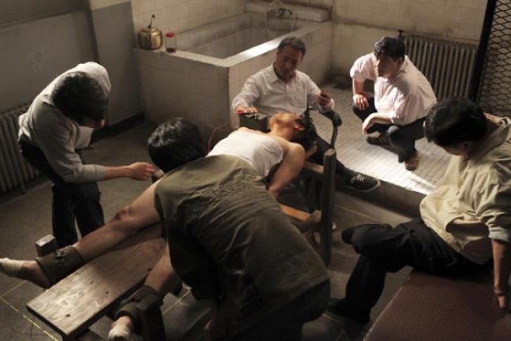 South Korean actor Lee Kyeong-yeong, third from right on a chair, acts as a torturer in a scene from the film <i>National Security</i>. Photo: AP