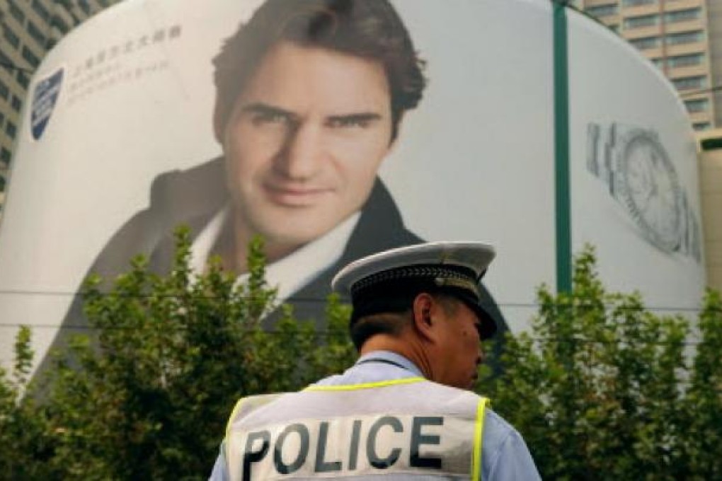 A policeman stands under a giant poster of top-ranked men's tennis player Roger Federer in Shanghai, who will be competing in the Shanghai Masters tennis tournament on Sunday. Photo: AFP