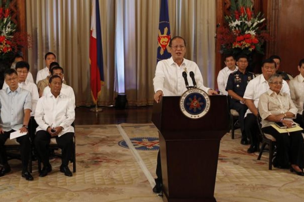 President Benigno Aquino announces the peace deal in a nationally televised address as cabinet officials sit behind him. Photo: EPA