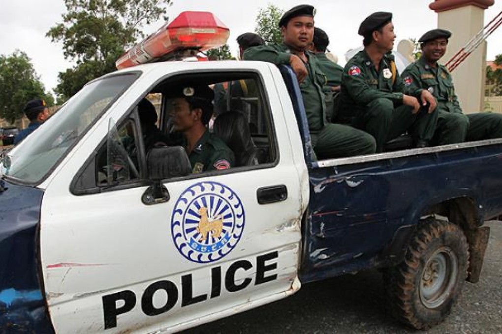 Cambodian police officers travel with a pick-up truck at the entrance of the Extraordinary Chambers in the Courts of Cambodia in Phnom Penh. Photo: EPA