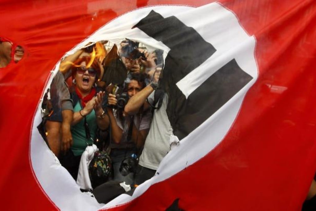 Demonstrators burn a Nazi flag during a demonstration against the visit of German Chancellor Angela Merkel in central Athens. Photo: Reuters