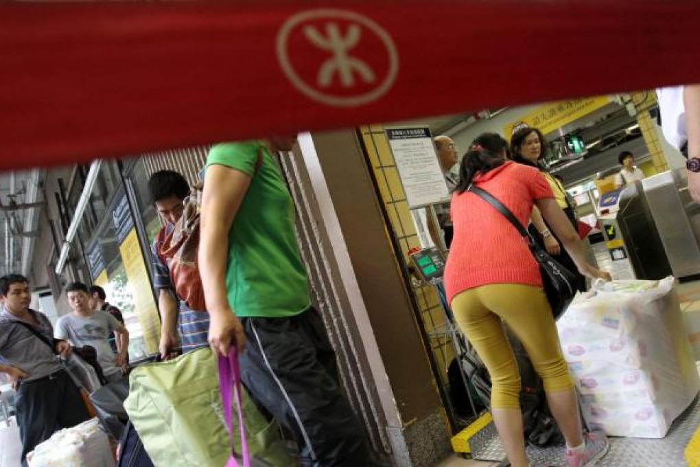 Passengers weigh their baggage at Sheung Shui MTR station after the new limit came into effect yesterday. Photo: K.Y. Cheng