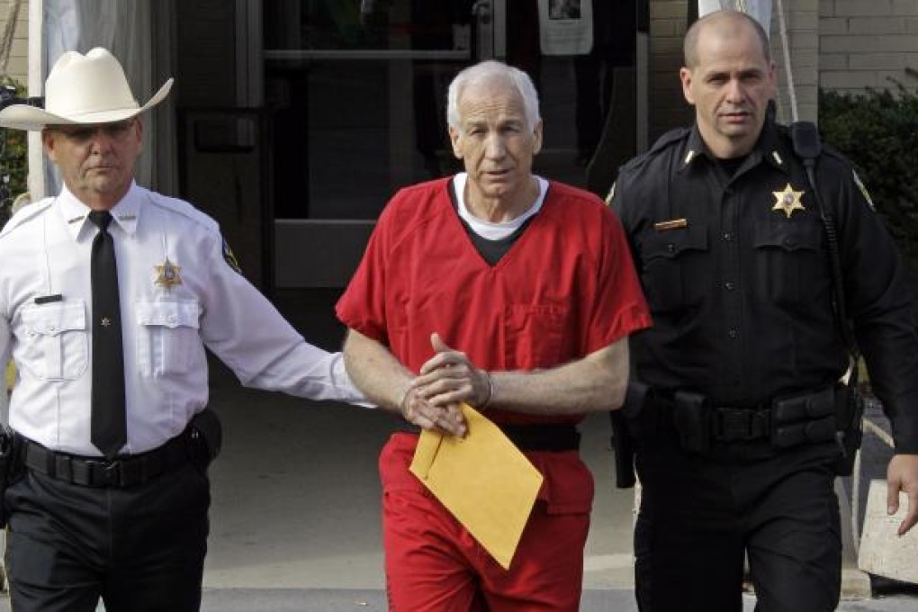 Jerry Sandusky (center) is escorted by police as he leaves the Centre County Courthouse.