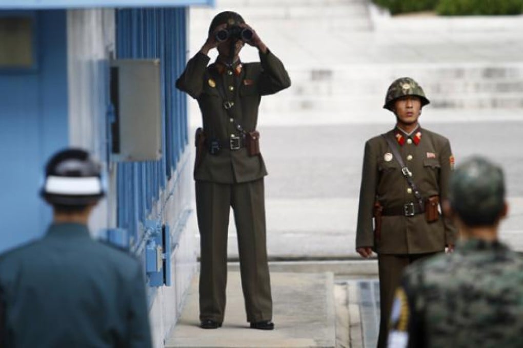 North Korean soldiers (back) look south as South Korean soldiers (foreground) stand guard at the border village of Panmunjom on October 9. Photo: AP