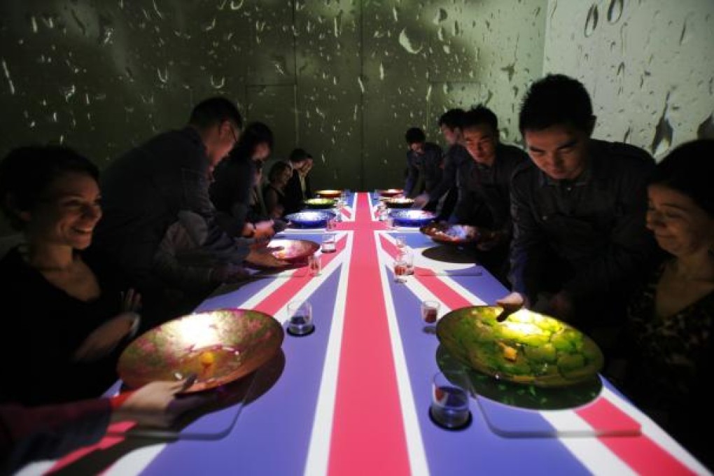 Guests are served dinner as a British flag is projected over the table of Ultraviolet restaurant in Shanghai June 23, 2012. Photo: Reuters