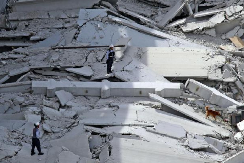 Emergency staff with a rescue dog search in the rubble of the garage in Doral, Florida, for trapped construction workers. Photo: MCT