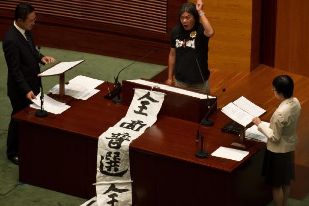 Legislator Leung Kwok-hung, aka "Long Hair", with a scroll demanding universal suffrage and retirement protection for all, makes a political statement at the swearing-in ceremony of the Hong Kong Legislative Council October 10, 2012. Photo: AFP