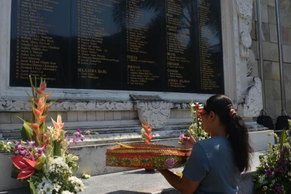 A Balinese woman lays an offering under a memorial monument for the 2002 Bali bombing built next to the site of the blasts.  Photo: AFP