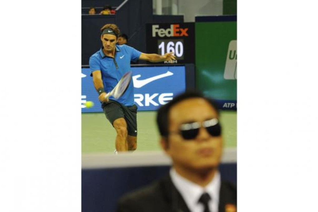 A security guard keeps watch as Roger Federer plays Lu Yen-hsun at the Shanghai Masters. Photo: AFP