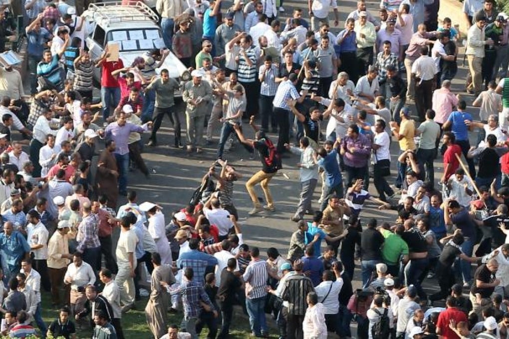 Egyptian Muslim Brotherhood protesters, left, throw stones at opponents of President Mohammed Mursi as they clash in Tahrir Square. Photo: EPA