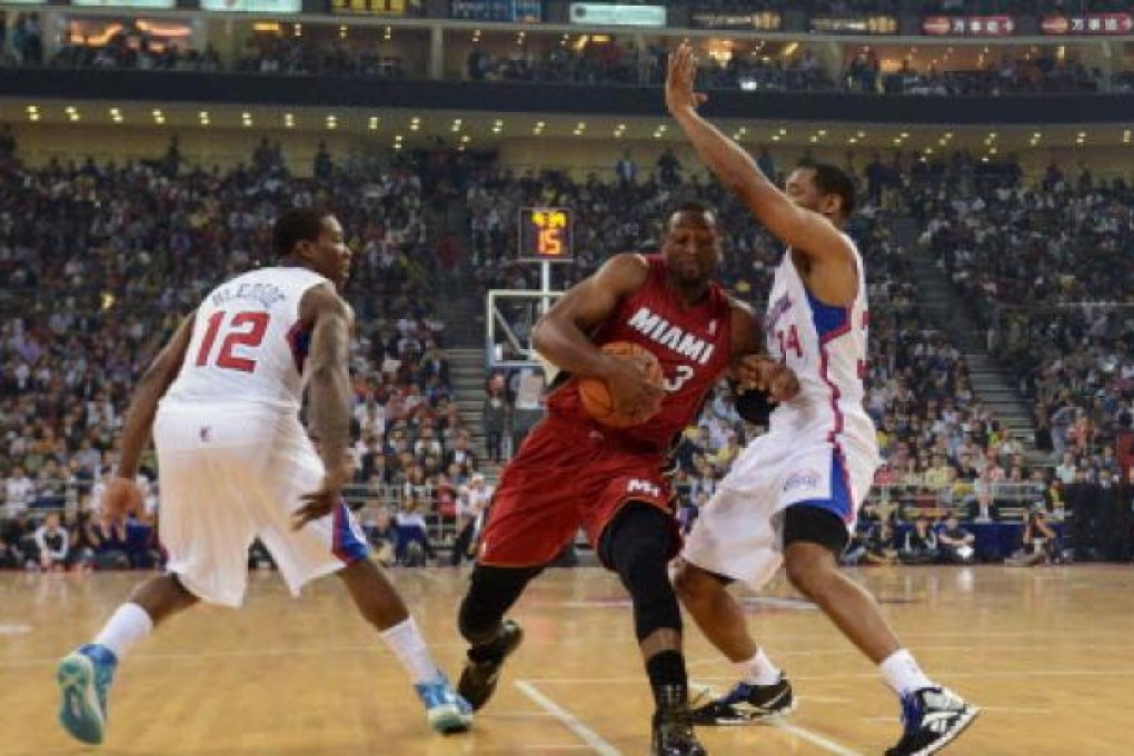 Eric Bledsoe (left) and Willie Green of the Los Angeles Clippers try to stop Dwyane Wade (centre) of Miami Heat during their NBA China Games basketball game in Beijing on Thursday.
