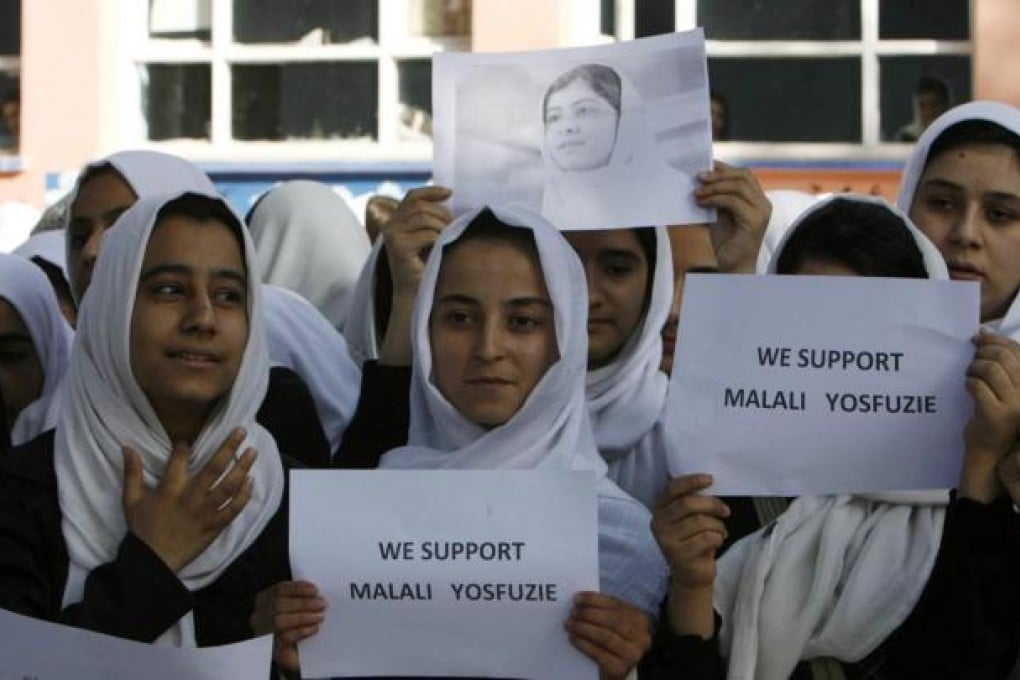Afghan students hold a portrait of Malala Yousafzai during prayers for her speedy recovery in Herat yesterday. Photo: EPA