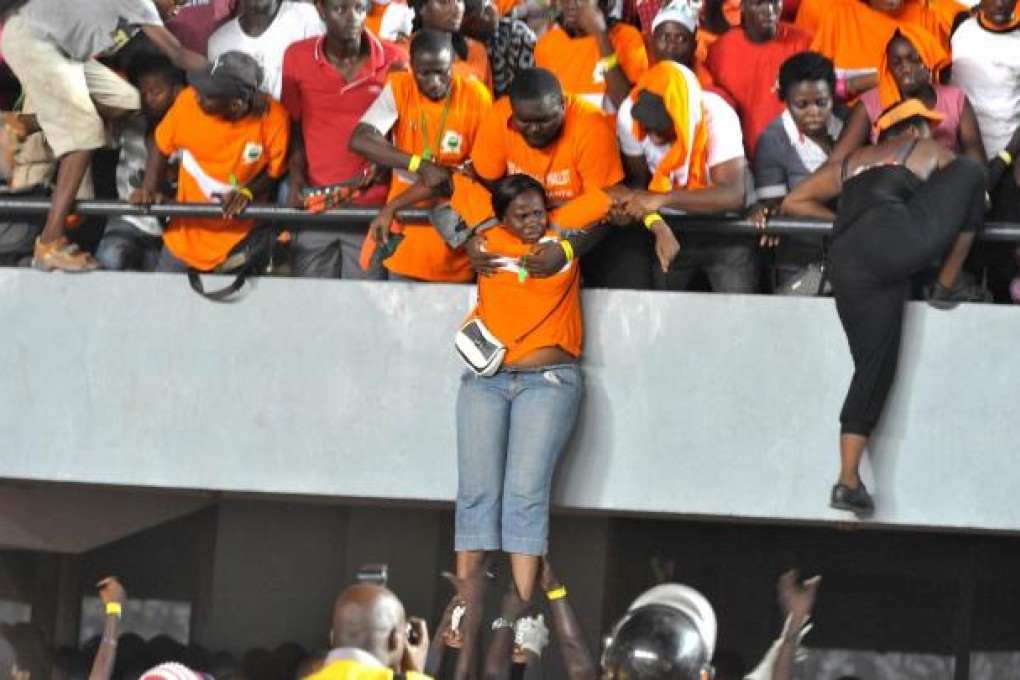 Ivory Coast fans are evacuated onto the pitch as Senegal supporters go on a rampage at Stade Leopold Sedar Senghor in Dakar. Photo: AFP