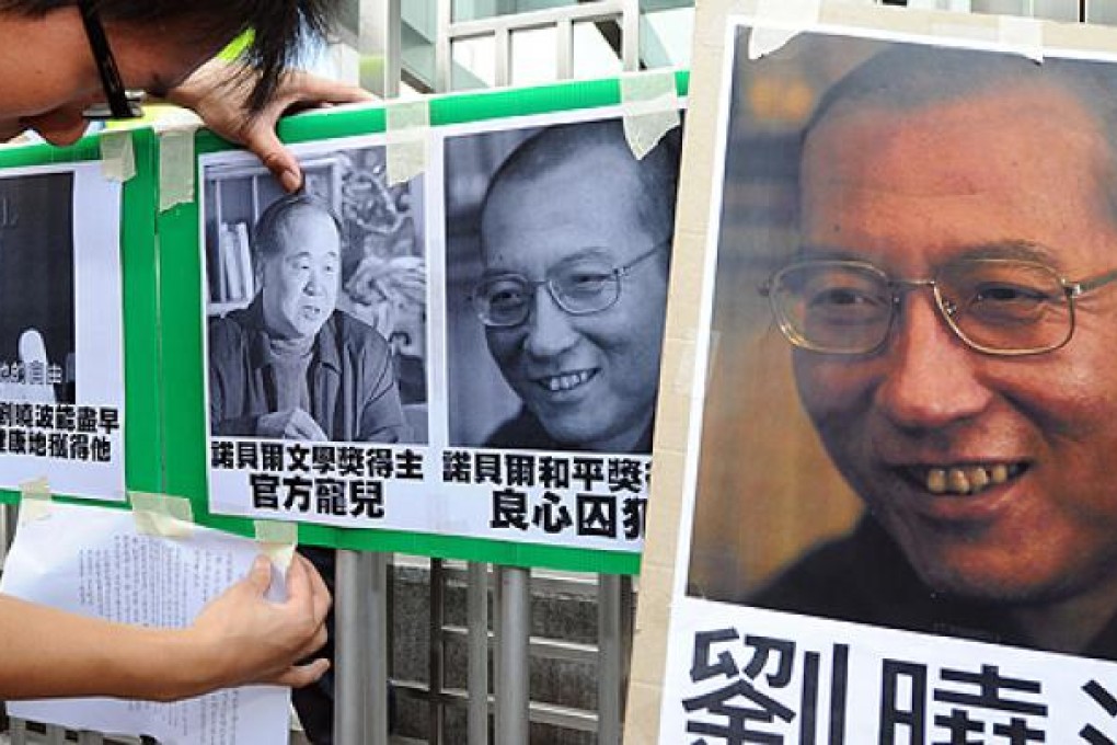 A protester tapes images of Mo Yan (left) and Liu Xiaobo to a gate during a demonstration in front of the Chinese liaison offices in Hong Kong on Saturday. Photo: AFP