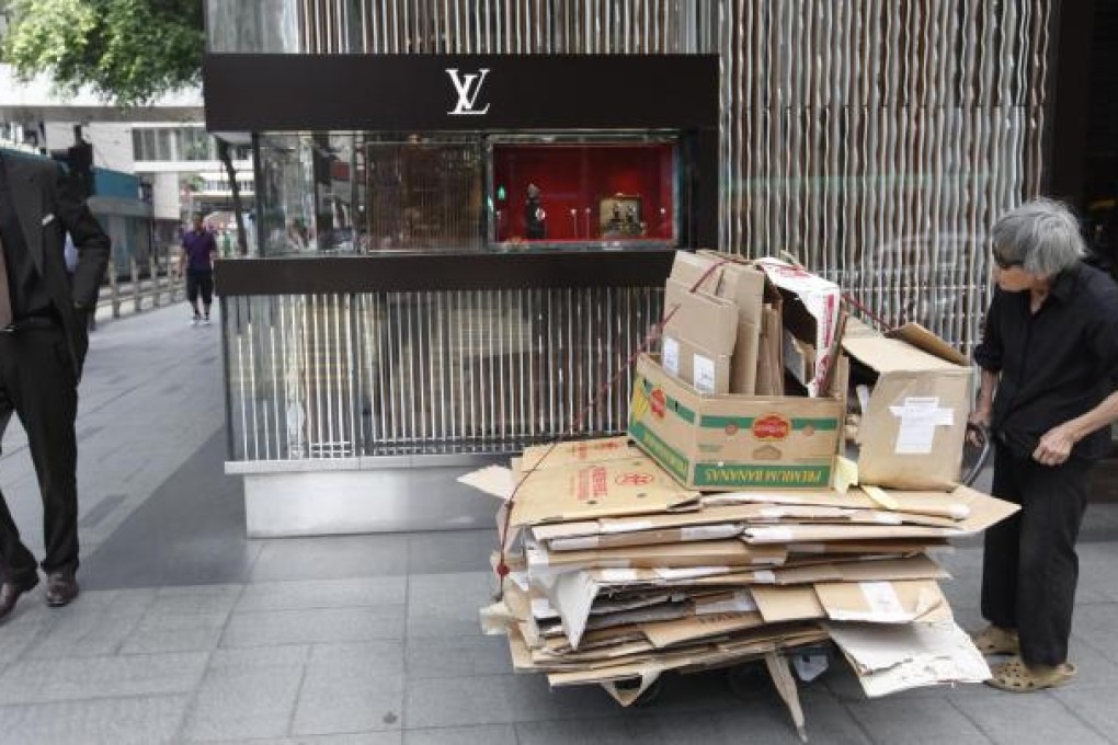 An elderly woman in Central pushes a trolley loaded with cardboard boxes for recycling, a means of earning some extra cash. Photo: EPA