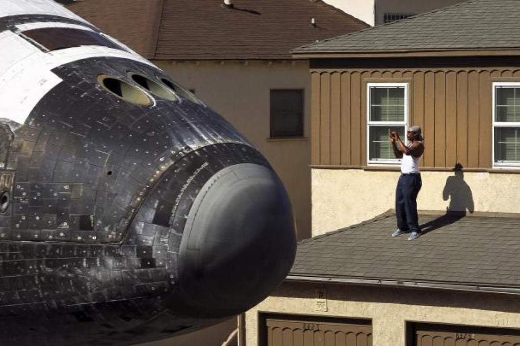 A man photographs Endeavour as it passes by. Photo: Reuters