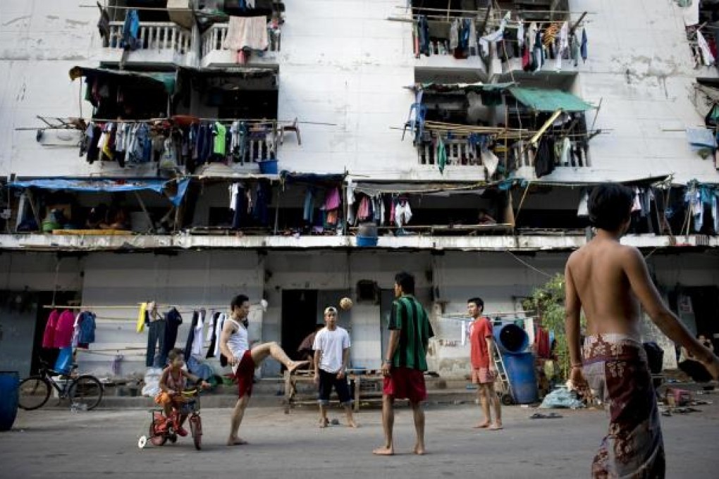 Myanmese migrant workers play outside their rundown home in a minority settlement in Mahachai, on the outskirts of Bangkok. Photo: AFP