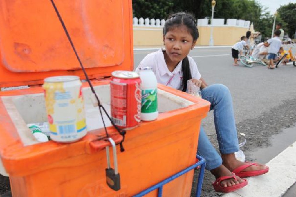 A young Cambodian girl sells drinks by a road in Phnom Penh. Photo: EPA